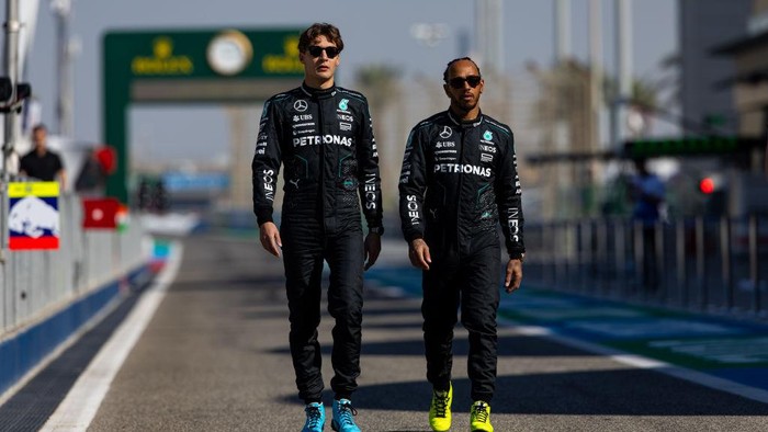 BAHRAIN, BAHRAIN - FEBRUARY 21: George Russell of Great Britain and Mercedes AMG and Lewis Hamilton of Great Britain and Mercedes AMG walk down pitlane together during day one of F1 Testing at Bahrain International Circuit on February 21, 2024 in Bahrain, Bahrain. (Photo by Kym Illman/Getty Images)
