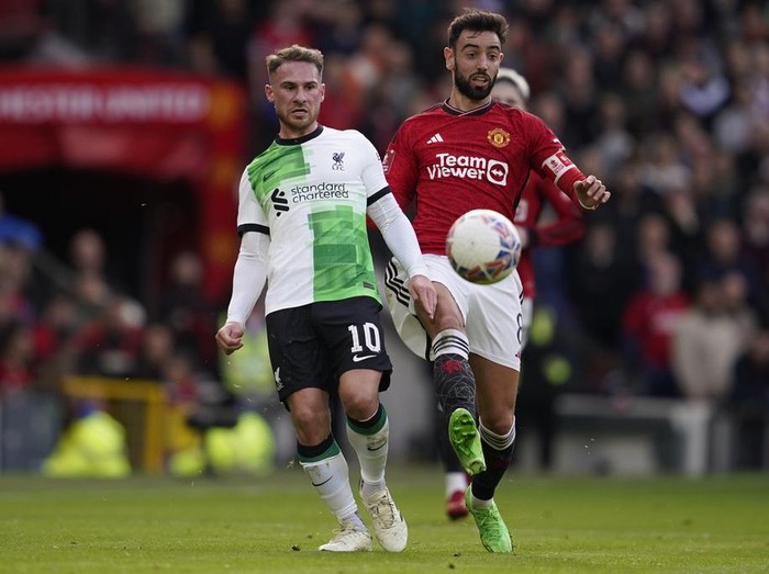 Liverpools Alexis Mac Allister, left, is challenged by Manchester Uniteds Bruno Fernandes during the FA Cup quarterfinal soccer match between Manchester United and Liverpool at the Old Trafford stadium in Manchester, England, Sunday, March 17, 2024. (AP Photo/Dave Thompson)