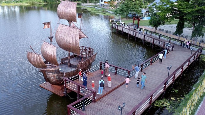 Sejumlah warga berfoto di wahana perahu tembaga di objek wisata Danau Perintis, Bone Bolango, Gorontalo, Minggu (17/3/2024). Objek wisata tersebut menjadi salah satu lokasi tujuan warga untuk menunggu waktu berbuka puasa atau ngabuburit, karena memiliki berbagai wahana, pemandangan alam hingga kuliner. ANTARA FOTO/Adiwinata Solihin/nym.