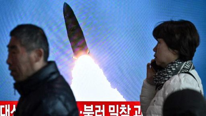 People walk past a television showing a news broadcast with file footage of a North Korean missile test, at a railway station in Seoul on March 18, 2024. North Korea fired a ballistic missile on March 18, Seouls military said, as US Secretary of State Antony Blinken visited South Korea to meet top officials and attend a democracy summit. (Photo by Anthony WALLACE / AFP)