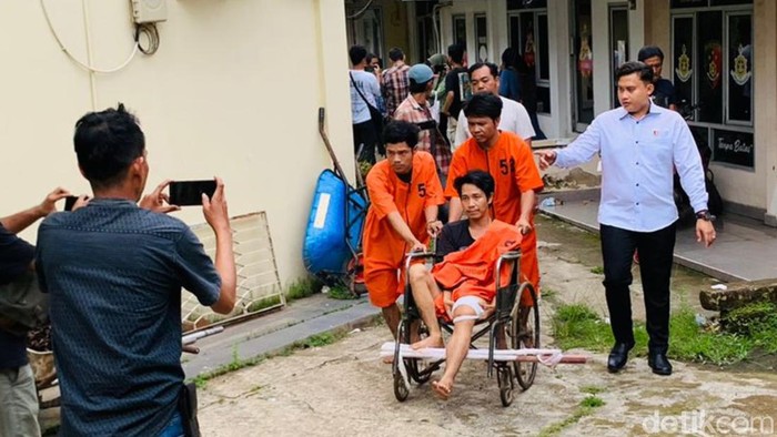 Budi berkursi roda didorong Ibrahim dan Joni di Jatanras Polda Sumsel.