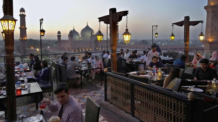 Indahnya Buka Puasa Ditemani Pemandangan Masjid Bersejarah Pakistan People break their fasts during the Muslim's holy fasting month of Ramadan, at a rooftop restaurant near the historical Badshahi mosque, in background, in Lahore, Pakistan, Friday, March 15, 2024. (AP Photo/K.M. Chaudary)
