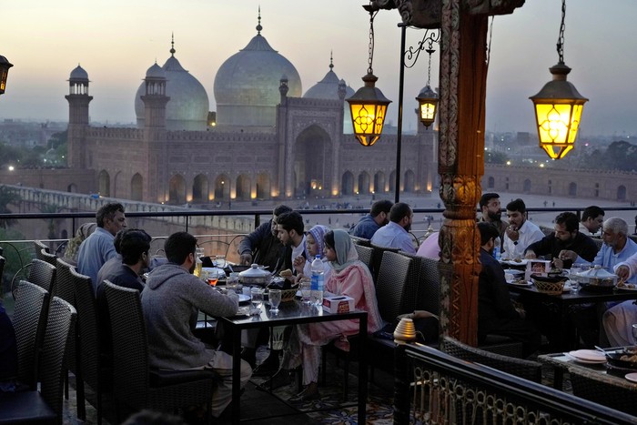 People break their fasts during the Muslims holy fasting month of Ramadan, at a rooftop restaurant near the historical Badshahi mosque, in background, in Lahore, Pakistan, Friday, March 15, 2024. (AP Photo/K.M. Chaudary)