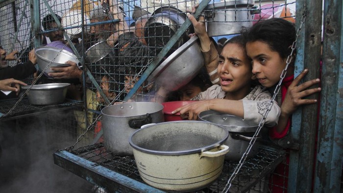 Kasihan, Anak-anak Gaza Berdesakan Minta Makan untuk Buka Puasa Palestinians line up to receive free meals at Jabaliya refugee camp in the Gaza Strip on Monday, March 18, 2024. (AP Photo/Mahmoud Essa)