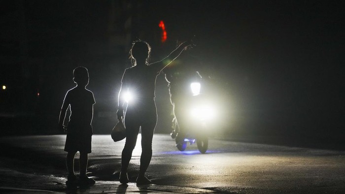 People walk during a scheduled power outage in Bauta, Cuba, Monday, March 18, 2024 The country is facing an energy crisis, with waves of blackouts worsening in recent weeks. (AP Photo/Ramon Espinosa)
