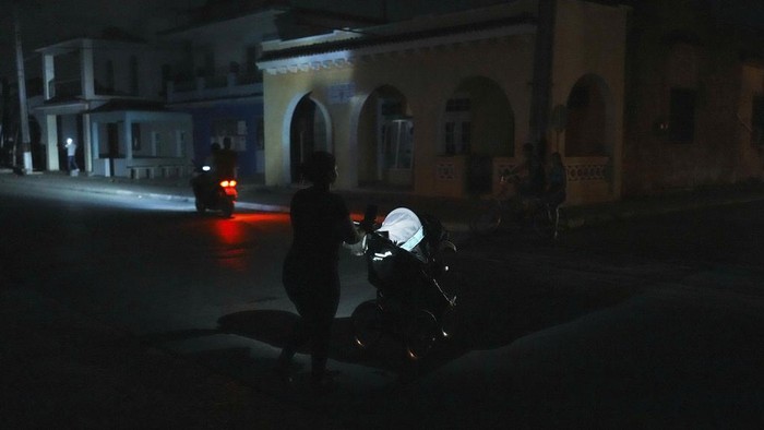 People walk during a scheduled power outage in Bauta, Cuba, Monday, March 18, 2024 The country is facing an energy crisis, with waves of blackouts worsening in recent weeks. (AP Photo/Ramon Espinosa)