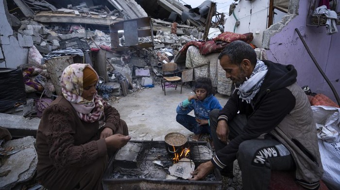 Momen Keluarga di Rafah Buka Puasa di Rumahnya yang Hancur Members of the Al-Rabaya family break their fast during the Muslim holy month of Ramadan outside their destroyed home by the Israeli airstrikes in Rafah, Gaza Strip, Monday, March 18, 2024. (AP Photo/Fatima Shbair)