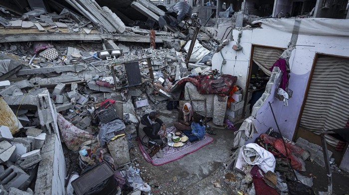 Members of the Al-Rabaya family break their fast during the Muslim holy month of Ramadan outside their destroyed home by the Israeli airstrikes in Rafah, Gaza Strip, Monday, March 18, 2024. (AP Photo/Fatima Shbair)