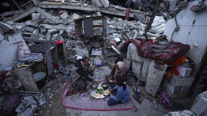 Members of the Al-Rabaya family break their fast during the Muslim holy month of Ramadan outside their destroyed home by the Israeli airstrikes in Rafah, Gaza Strip, Monday, March 18, 2024. (AP Photo/Fatima Shbair)