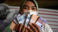 Warga menunjukkan uang rupiah baru pecahan kecil yang telah ditukarkan dari mobil kas keliling Bank Indonesia (BI) di Pasar Pramuka, Jakarta, Senin (18/3/2024).