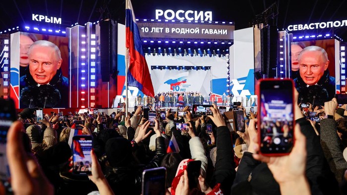 Putin Gelar Konser Kemenangan Pemilu dan Peringatan Aneksasi Krimea Russian incumbent President Vladimir Putin, who was declared winner of the presidential election by the country's electoral commission, is seen on screens as he delivers a speech on the stage during a rally, which marks the 10th anniversary of Russia's annexation of Crimea from Ukraine, in Red Square in central Moscow, Russia, March 18, 2024. REUTERS/Stringer