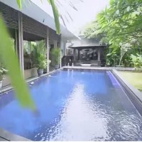 Halaman belakang difungsikan untuk kolam renang dan tempat untuk bersantai. Pepohonan rindang, salah satunya sudah berusia ratusan tahun yang didatangkan langsung dari Bali, makin meneduhkan suasana. (Foto: YouTube/Trans7 Official)