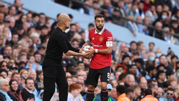 MANCHESTER, ENGLAND - OCTOBER 02: Pep Guardiola the head coach / manager of Manchester City passes the ball to Bruno Fernandes of Manchester United during the Premier League match between Manchester City and Manchester United at Etihad Stadium on October 2, 2022 in Manchester, United Kingdom. (Photo by Matthew Ashton - AMA/Getty Images)