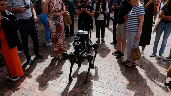 Potret Robot Anjing yang Bakal Atur Lalu Lintas di Spanyol People watch a police robot dog aimed at helping enforce traffic laws for E-scooters, during its presentation to the media, in Malaga, southern Spain March 19, 2024. REUTERS/Jon Nazca