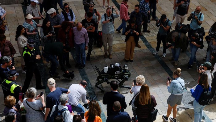 Potret Robot Anjing yang Bakal Atur Lalu Lintas di Spanyol People watch a police robot dog aimed at helping enforce traffic laws for E-scooters, during its presentation to the media, in Malaga, southern Spain March 19, 2024. REUTERS/Jon Nazca