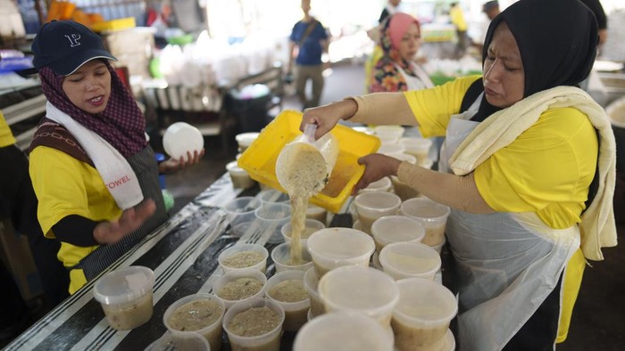 A woman packs Bubur Lambuk porridge into at Kampung Baru village in Kuala Lumpur, Malaysia, Wednesday, March 20, 2024. Bubur Lambuk is a type of Malay rice porridge that is cooked and distributed in many places during the fasting month of Ramadan. (AP Photo/Vincent Thian)