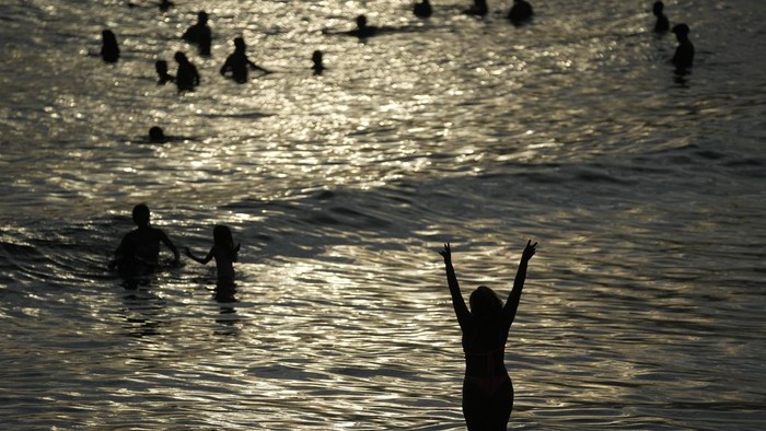 People cool off in the waters of Arpoador beach amid a heat wave, in Rio de Janeiro, Brazil, Wednesday, March 20, 2024. (AP Photo/Silvia Izquierdo)