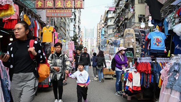 Orang-orang melangkah melalui jalan pasar di distrik Kowloon, Hong Kong pada 27 Februari 2024, sehari sebelum anggaran tahunan kota tersebut diumumkan pada 28 Februari. (Photo by Peter PARKS / AFP)