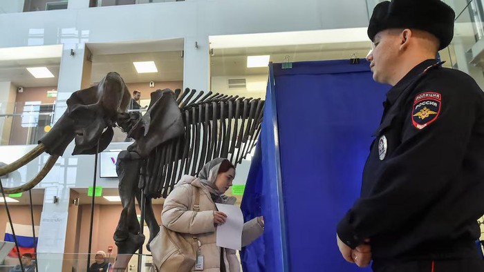 A woman walks into a voting booth near a giant mammoth skeleton at a polling station located in Novosibirsk State University, on the final day of the presidential election in Novosibirsk, Russia, March 17, 2024. REUTERS/Vladislav Nekrasov Purchase Licensing Rights, opens new tab