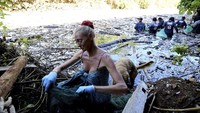 Seorang relawan asing memungut sampah di sungai yang dipenuhi sampah di Pecatu, Bali, Indonesia pada Jumat, 22 Maret 2024.