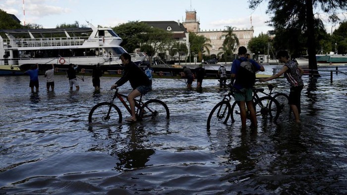A person on a bike pedals through a street flooded due to the rise in water levels of the Rio de la Plata river, in Tigre, on the outskirts of Buenos Aires, Argentina, Thursday, March 21, 2024. (AP Photo/Rodrigo Abd)