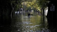 Seorang warga mengayuh kano menyelusuri banjir. 