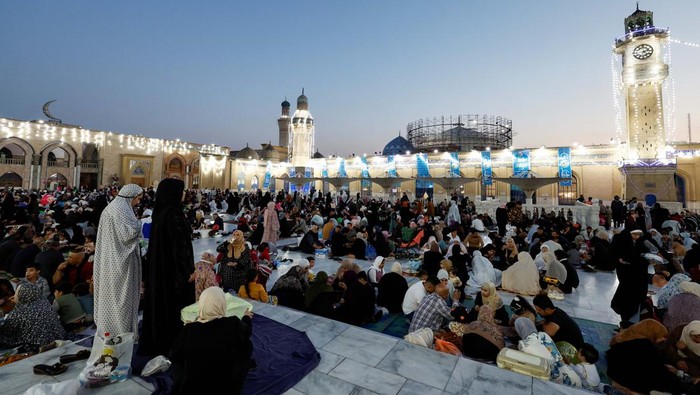Iraqi Muslims eat Iftar, the meal to end their fast at sunset, during the holy fasting month of Ramadan at the shrine of cleric Sheikh Abdul Qadir al-Gailani in Baghdad, Iraq, March 21, 2024. REUTERS/Thaier Al-Sudani