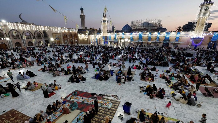 Iraqi Muslims eat Iftar, the meal to end their fast at sunset, during the holy fasting month of Ramadan at the shrine of cleric Sheikh Abdul Qadir al-Gailani in Baghdad, Iraq, March 21, 2024. REUTERS/Thaier Al-Sudani