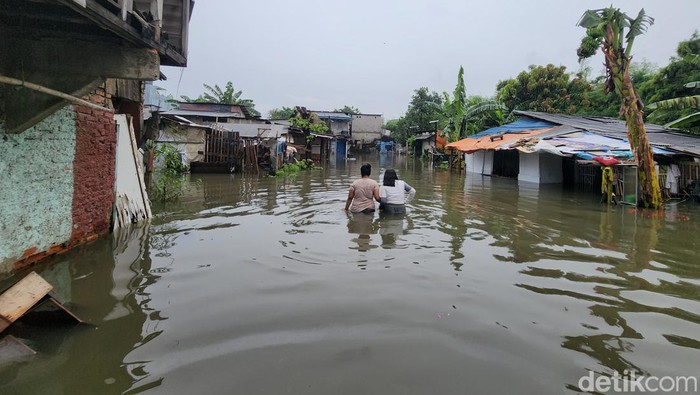 Warga beraktivitas di tengah banjir yang merendam sebagian rumah di RT6/6 Kelurahan Cengkareng Barat, Kecamatan Cengkareng, Jakarta Barat, Jumat (22/3/2024) pukul 12.00 WIB.
