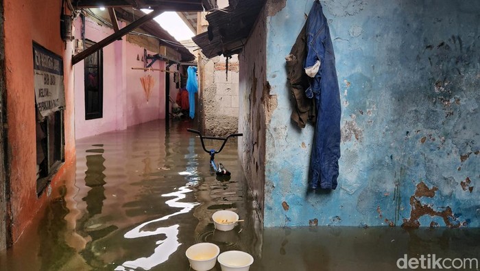Warga beraktivitas di tengah banjir yang merendam sebagian rumah di RT6/6 Kelurahan Cengkareng Barat, Kecamatan Cengkareng, Jakarta Barat, Jumat (22/3/2024) pukul 12.00 WIB.
