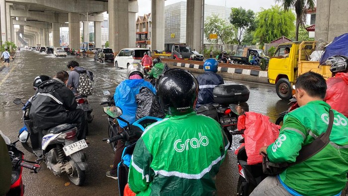 Pengendara motor yang berhenti menunggu air surut di Jalan Boulevard Barat, Jakut