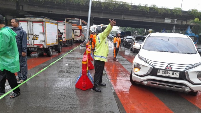Polisi mengalihkan arus lalu lintas di Jalan Daan Mogot, Cengkareng, Jakarta Barat imbas banjir.