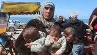 Seorang wanita Palestina membawa anak kembar tiganya mengungsi ke wilayah selatan, 21 Maret 2024.