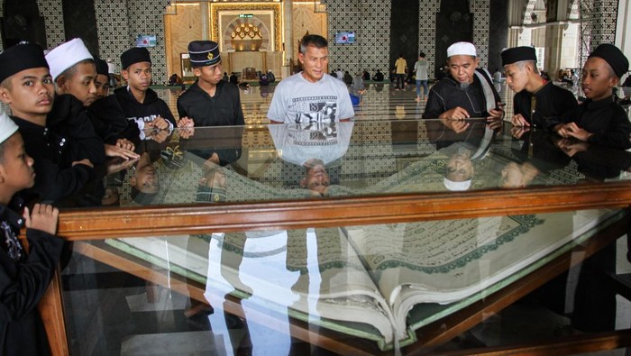 Jamaah melihat Al Quran berukuran raksasa di Masjid Raya Makassar, Sulawesi Selatan, Sabtu (23/3/2024). Al Quran yang ditulis oleh pendiri Pondok Pesantren Al-Asy'ariah Wonosobo, Jawa Timur KH Ahmad Faqih Al-Muntaha tersebut berukuran 1 x 1,5 meter dan menjadi daya tarik wisata religi di daerah itu. ANTARA FOTO/Arnas Padda/rwa.