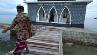 Jamaah berjalan di jembatan kayu usai menjalankan salat di masjid Taman Surga Al Muqorramah di Dusun Kaudalani, Desa Tanailandu, Buton Tengah, Sulawesi Tenggara.