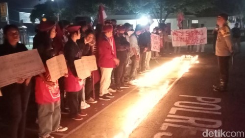 Puluhan mahasiswa yang tergabung dalam Cipayung Flores Timur menggelar aksi seribu lilin di depan Kantor Polres Flores Timur, Sabtu (23/3/2024). (Foto: Yurgo Purab/detikBali)