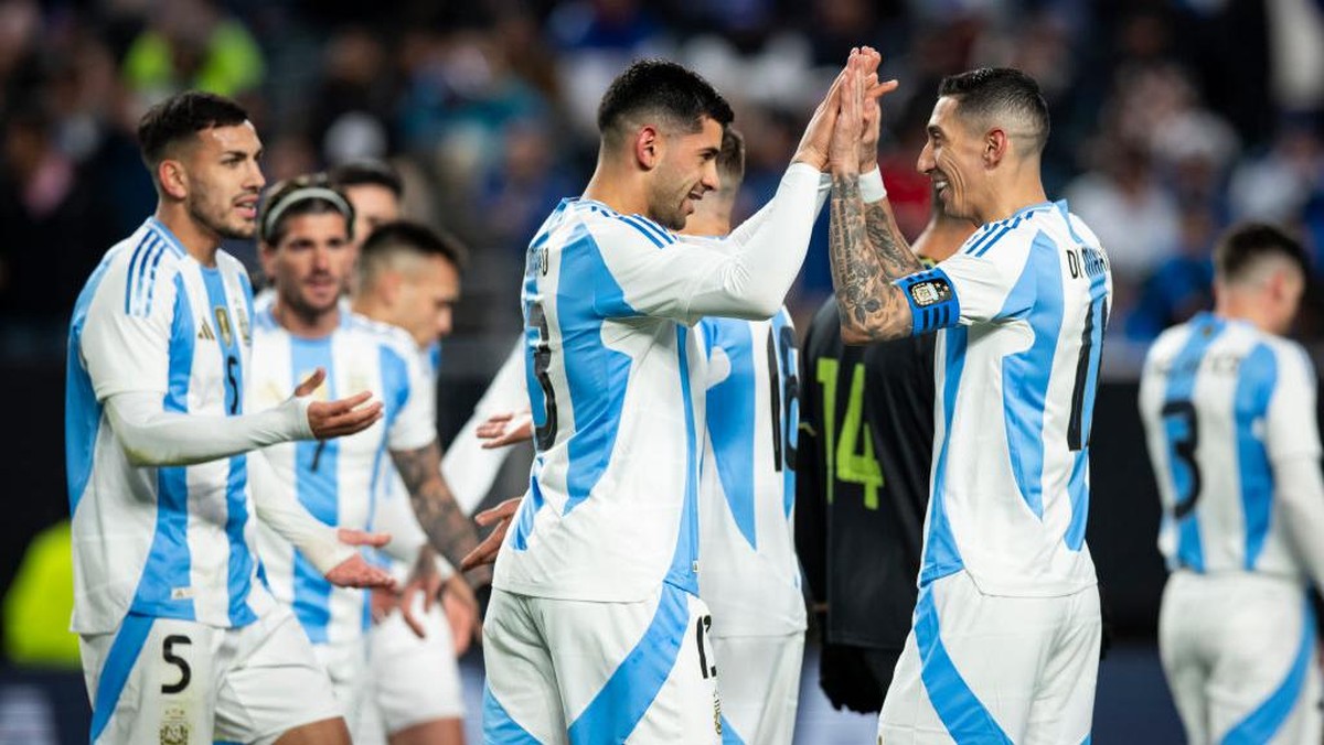 Angel Di Maria (kanan) menghampiri Cristian Romero (tengah) yang mencetak gol pertama Argentina. Foto: Getty Images/Ira L. Black