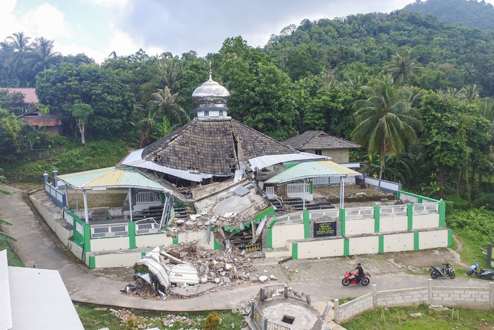 Warga melintas di dekat Masjid Jamik Al Muhajirin yang sebangian bangunannya roboh akibat gempa di Dusun Balikbakgunung, Sangkapura, Pulau Bawean, Gresik, Jawa Timur, Minggu (24/3/2024). Badan Penanggulangan Bencana Daerah (BPBD) Gresik mencatat sebanyak 4.085 rumah, 138 rumah ibadah, 68 sekolah, dan 12 perkantoran di Kecamatan Sangkapura dan Tambak mengalami kerusakan akibat gempa bumi yang berpusat di Kabupaten Tuban, Jawa Timur. ANTARA FOTO/Rizal Hanafi/Spt.