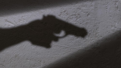 A shadow of a hand holding a gun in his hand.