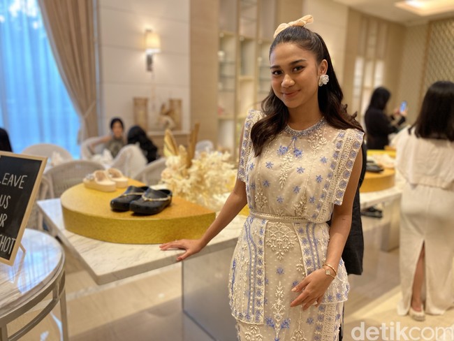 Zize, begitu sapaan akrabnya, muncul dalam balutan terusan lurus putih tanpa lengan dari jenama Boh Play. Gaun berpeplum asimetris tersebut dihiasi detail brokat menawan bernuansa biru. (Foto: Daniel Ngantung/detikcom)