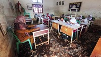 Para siswa mengikuti kegiatan belajar mengajar di ruang kelas yang lantainya masih dipenuhi lumpur sisa banjir.