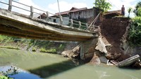 Seorang warga mengecek kondisi jembatan yang rusak akibat banjir di Desa Kalidawir, Tulungagung, Jawa Timur, Minggu (24/3/2024).