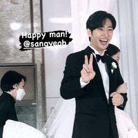 Di hari pernikahannya, Lee Sang Yeob tampil gagah memakai setelan jas hitam. Sedangkan istrinya tampil anggun dalam balutan gaun putih dan veil. Aura bahagia terpancar dari wajah Lee Sang Yeob saat menggandeng istrinya, melewati altar. Foto: dok. Instagram @all_for_yeob