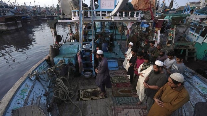 Pakistani fishermen attend prayer at a boat in the fish harbor on the Arabian Sea during the Muslim's holy fasting month of Ramadan, in Karachi, Pakistan, Sunday, March 24, 2024. (AP Photo/Fareed Khan)