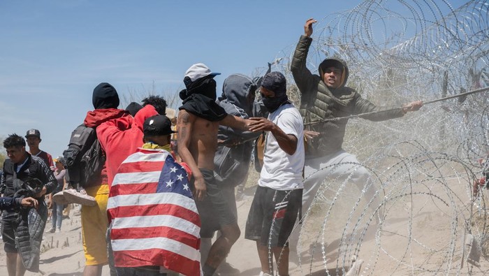 Potret Ratusan Imigran Terobos Kawat Berduri Serbu Perbatasan AS-Meksiko A group of migrants attempt to pull down the concertina wire deployed by Texas law enforcement officers, at the U.S.-Mexico border near El Paso, Texas, U.S., March 22, 2024. REUTERS/Justin Hamel