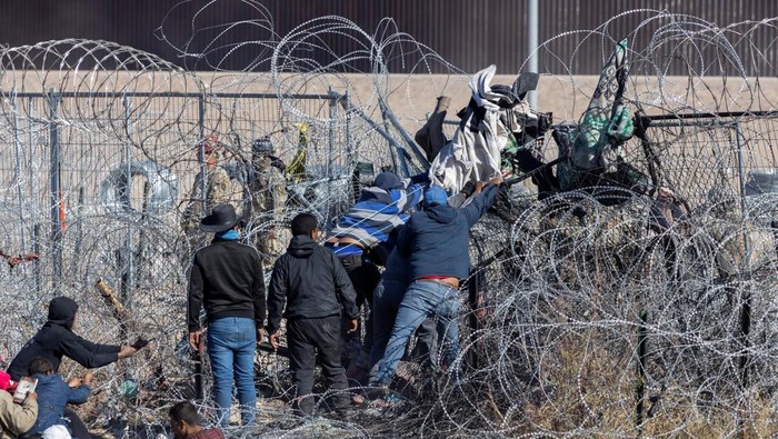 Potret Ratusan Imigran Terobos Kawat Berduri Serbu Perbatasan AS-Meksiko Migrants try to tear down a fence placed by members of the Texas Army National Guard to deter migrants from entering the U.S., as seen from Ciudad Juarez, Mexico, March 22, 2024. REUTERS/David Peinado