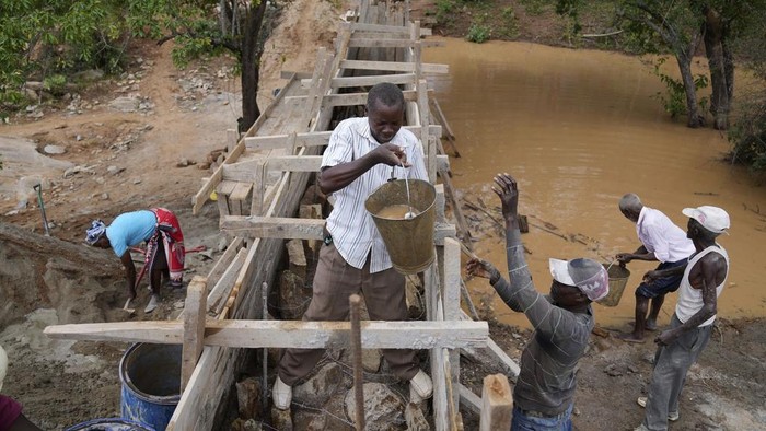 Warga Kenya Bikin Bendungan Pasir untuk Selamat dari Kekeringan Members of Kyemoo Power, a self-help group, construct a sand dam in Makueni County, Kenya on Thursday, Feb. 29, 2024. Building sand dams, a structure for harvesting water from seasonal rivers, helps minimize water loss through evaporation and recharges groundwater. (AP Photo/Brian Inganga)