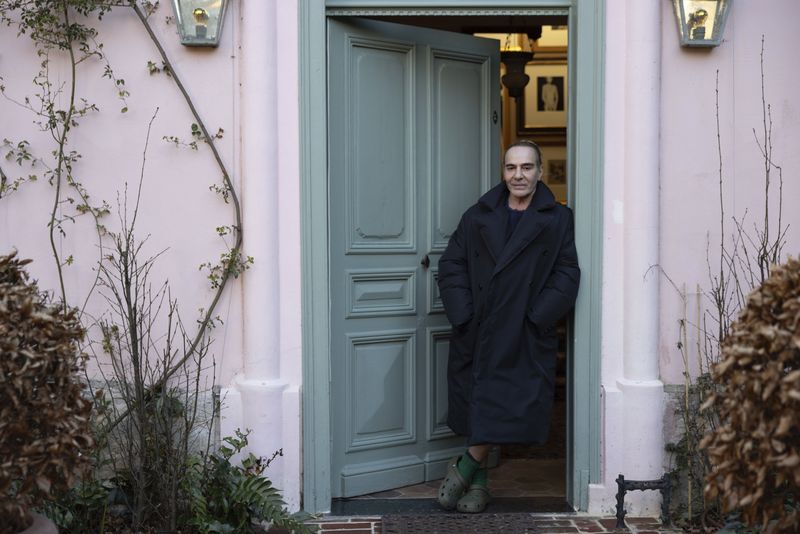 This image released by MUBI shows fashion designer John Galliano in the doorway of his home in a scene from the documentary film, 
