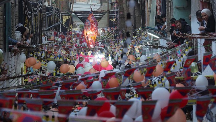 Egyptian residents of Ezbet Hamada in Cairo's Mataria district look out their windows and balconies to celebrate a mass ''Iftar'', the meal to end their fast at sunset, during the holy fasting month of Ramadan in Cairo, Egypt March 25, 2024. REUTERS/Amr Abdallah Dalsh