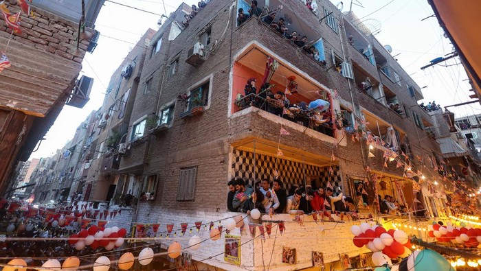 Egyptian residents of Ezbet Hamada in Cairo's Mataria district look out their windows and balconies to celebrate a mass ''Iftar'', the meal to end their fast at sunset, during the holy fasting month of Ramadan in Cairo, Egypt March 25, 2024. REUTERS/Amr Abdallah Dalsh